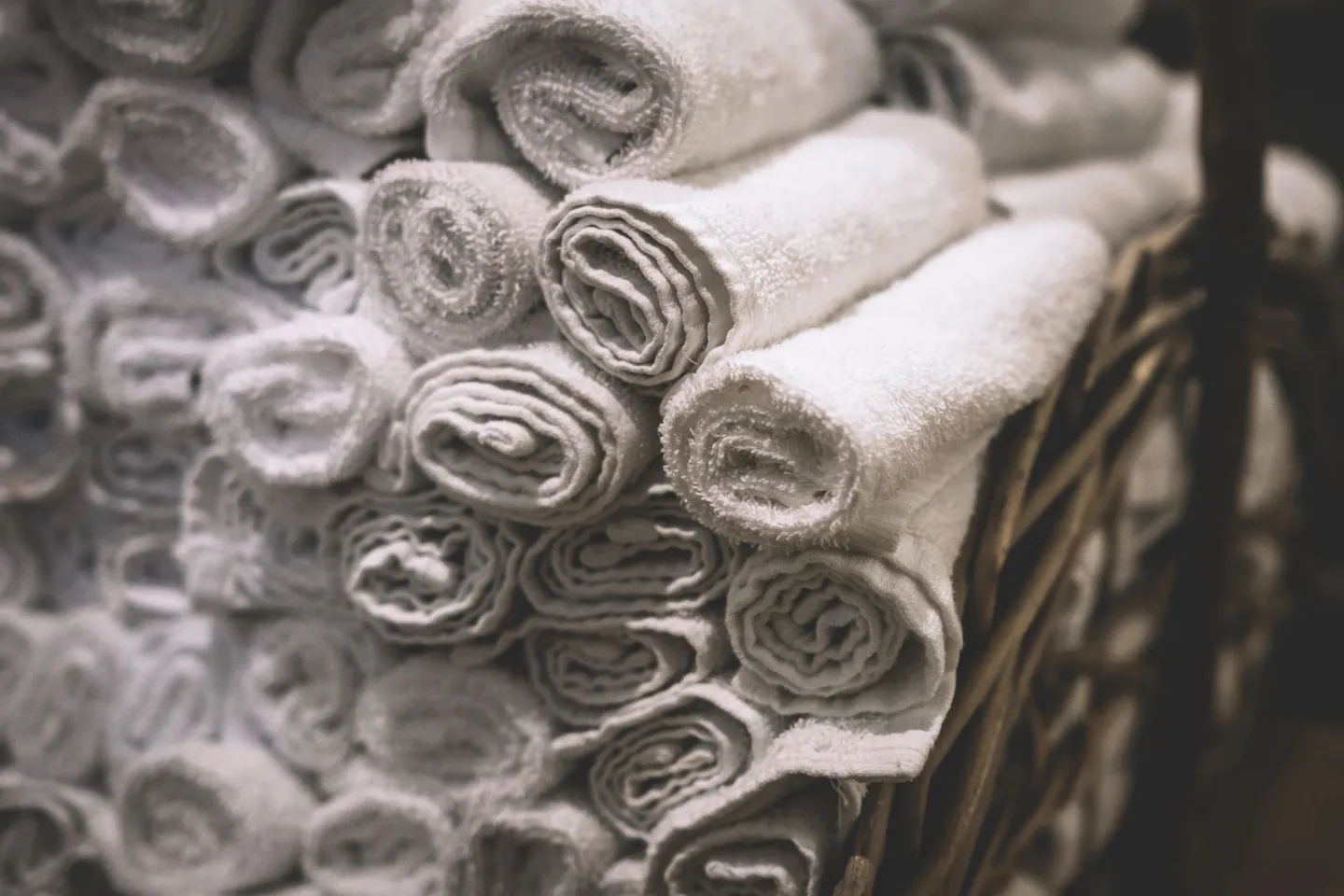 White towels rolled neatly inside a woven basket.